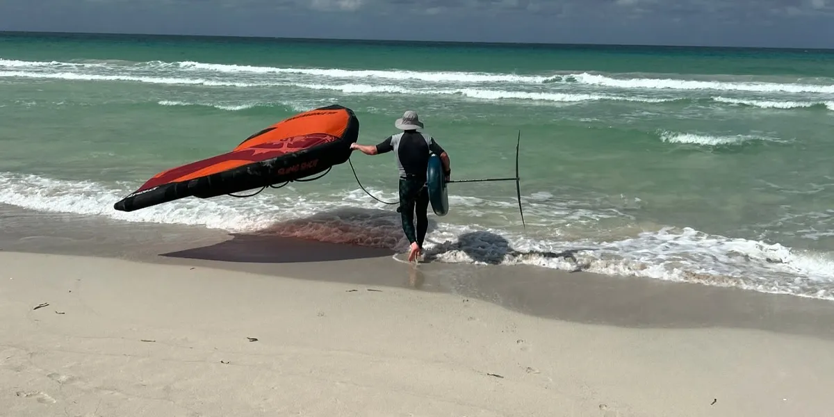 Rider de wing foil qui entre dans l'eau sur la plage de Varadero, Cuba
